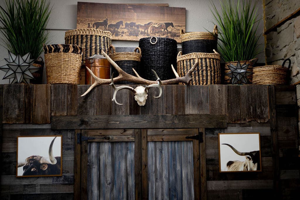 Antlers, woven baskets, and framed longhorn portraits arranged above a reclaimed barn-wood wall inside the cafe